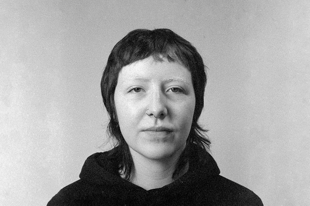 A black-and-white headshot of Feá McCoy. She has short, dark hair and wears a dark top.